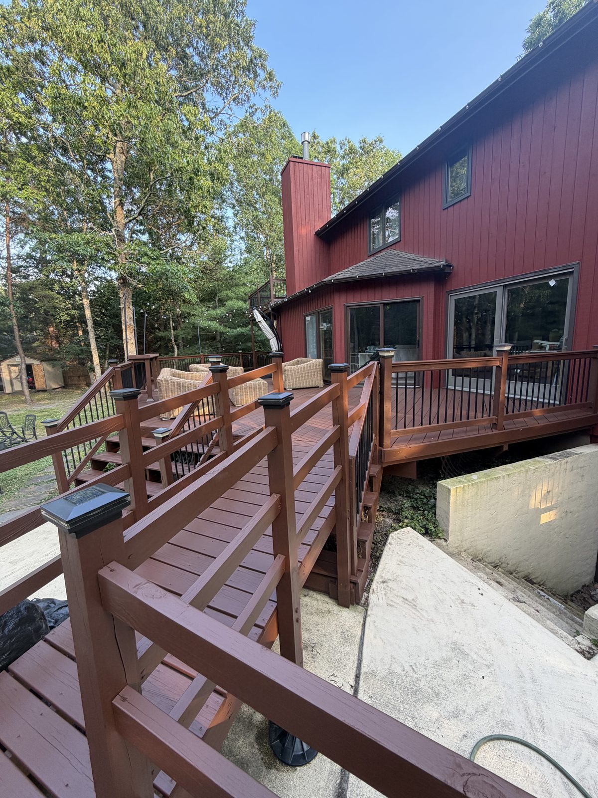 Freshly stained multi-level wood deck with dark red-brown finish and black railings