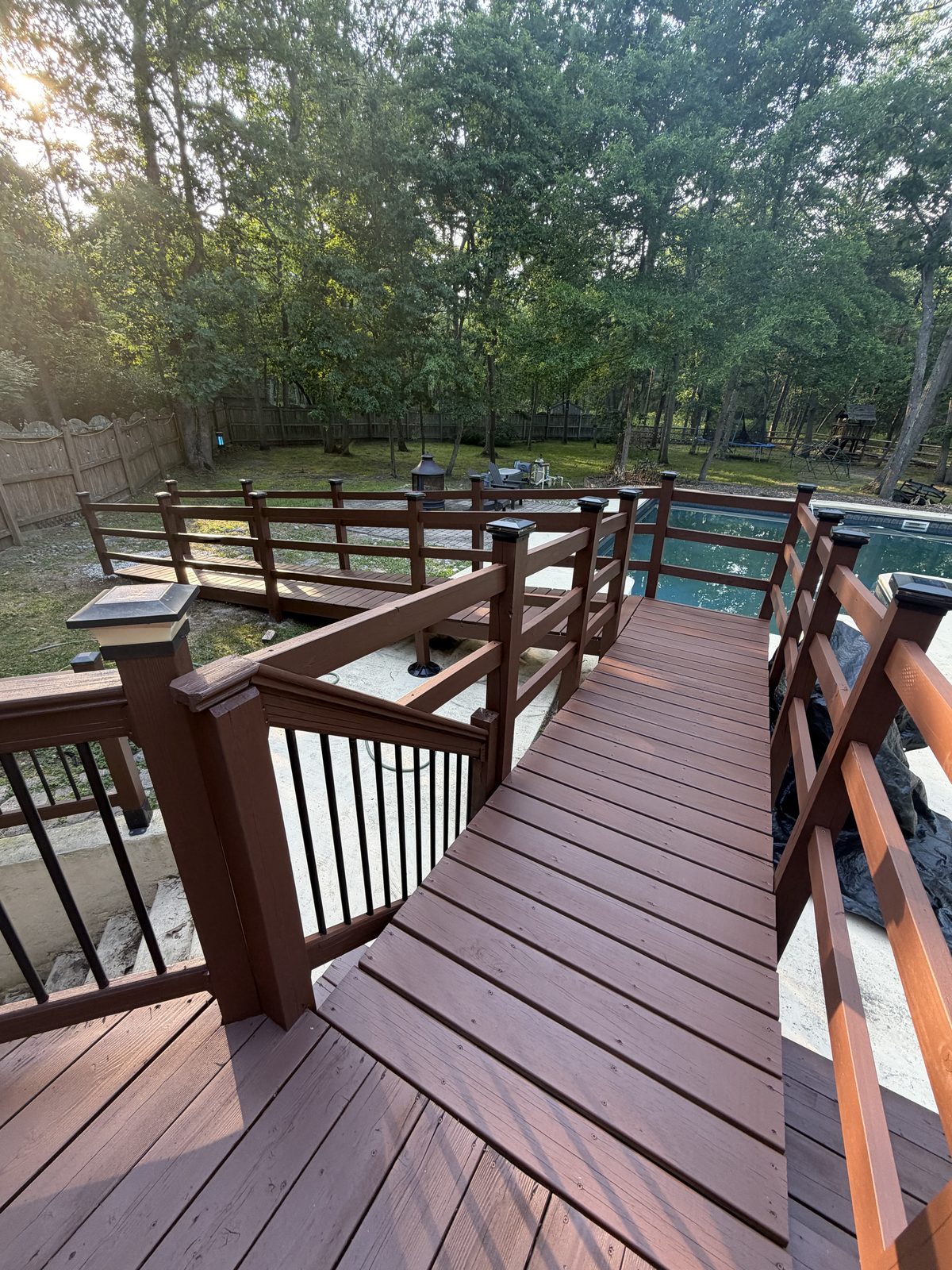 Freshly stained wood deck walkway leading to an in-ground pool