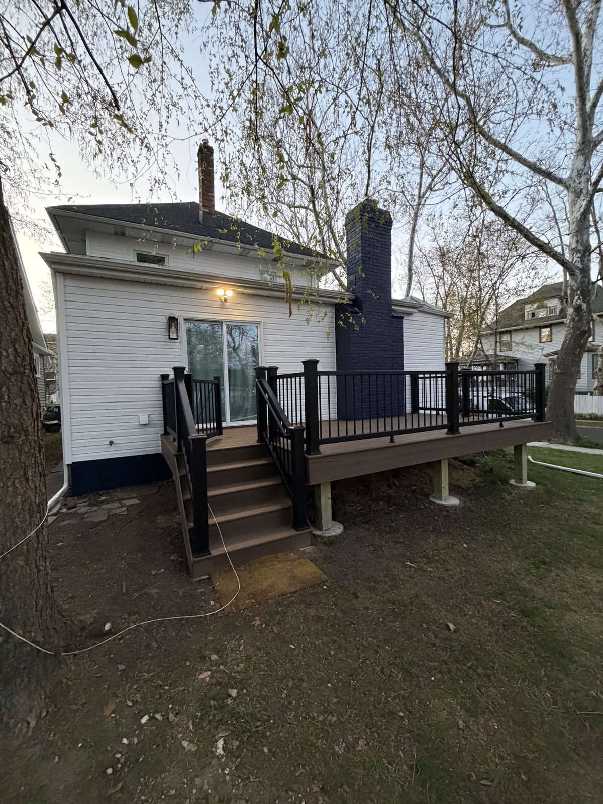 White siding home exterior with matching dark navy chimney and rear deck