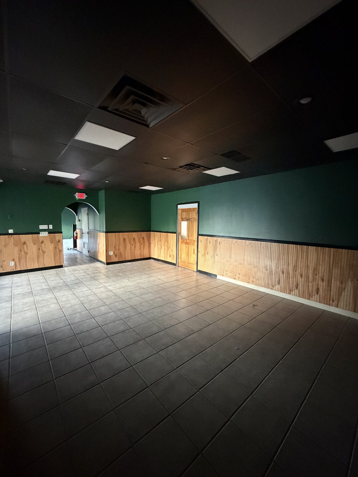 Freshly painted commercial space with dark green walls and wood wainscoting