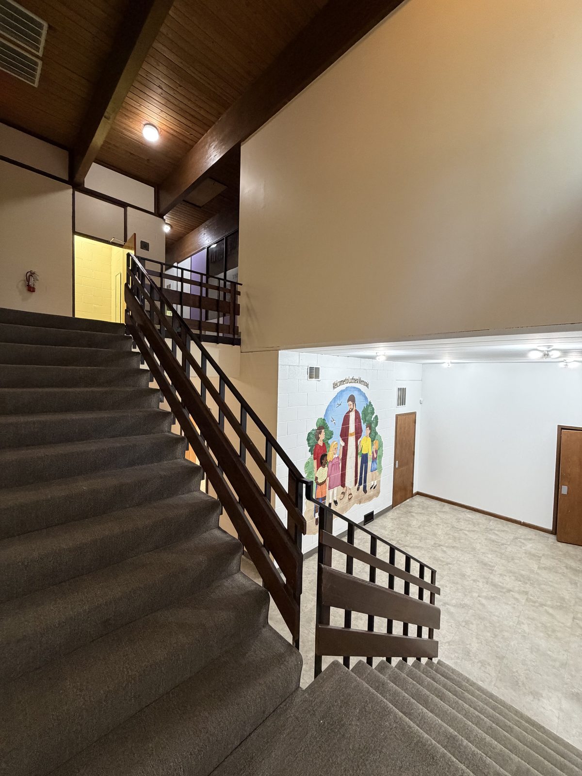 Freshly painted commercial stairwell with beige walls and dark wood-beam ceiling