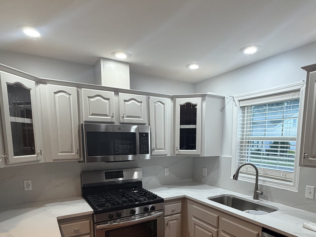 Kitchen after cabinet refinishing, with white painted cabinets